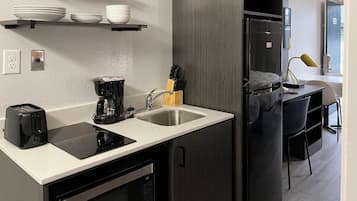 A compact kitchen with a built-in oven, a coffee maker, and a sink.