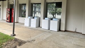 A laundromat with four washing machines and a Coca-Cola vending machine under a covered area with large windows. - Studio 6 Bay Minette, Al (Bay Minette)