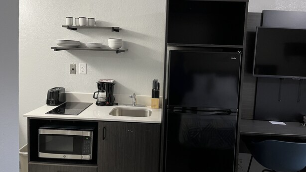 A compact kitchen with a microwave, toaster, coffee maker, and a refrigerator. - Studio 6 Bay Minette, Al (Bay Minette)