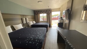 A hotel room with two beds, a desk, a television, and a window with curtains. - Executive Inn & Suites (Beaumont)