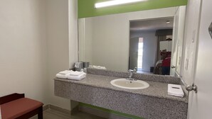 A bathroom with a granite countertop, two sinks, a bench, and a mirror. - Executive Inn & Suites (Beaumont)