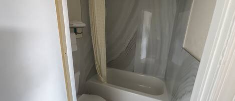 Un baño con inodoro, bañera y cortina de ducha.