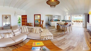 Un espacio habitable amplio con un sofá curvo, una mesa de centro de madera y una lámpara colgante.