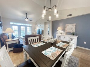 A dining area with a dark wooden table, white chairs, and decorative placemats.