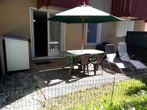 An outdoor patio with a table, chairs, and a sun umbrella.
