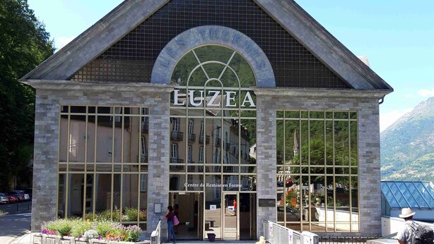 Un edificio con una amplia entrada arqueada y el nombre "LUZEA" visible en grande.