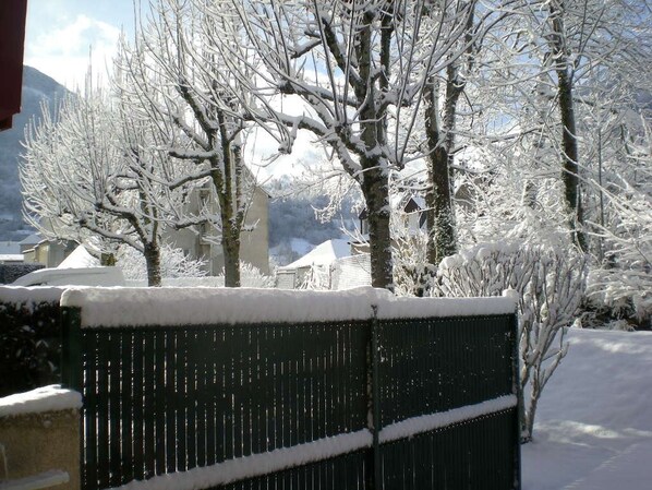 A snow-covered landscape with bare trees and a building in the background.