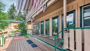 A wooden deck with outdoor furniture, a covered area with a table and chairs, and a view of a forested area. - Main St Red River Ski Condo w/ Mountain View! (Red River)