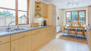 Una cucina moderna con mobili in legno, un lavello e un'area pranzo con tavolo e sedie.