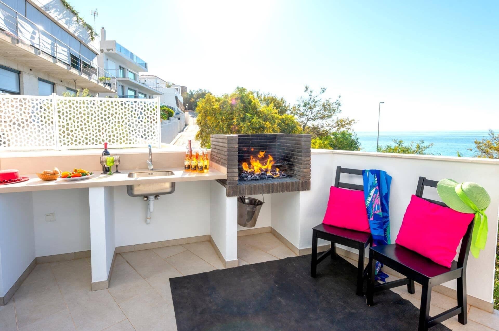 Un balcon équipé d’un barbecue, d’un évier et de deux chaises.