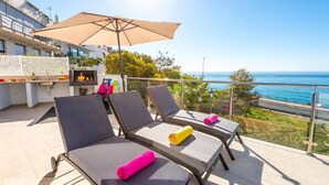 A balcony with four lounge chairs, a table, and a large umbrella.