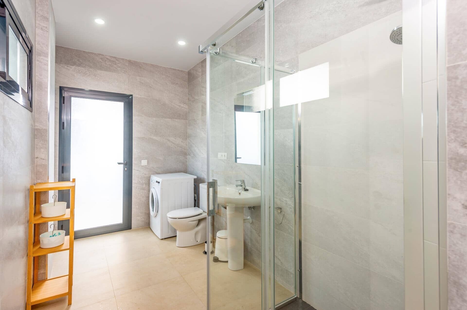 A modern bathroom with a glass shower enclosure, a built-in sink, and a toilet.