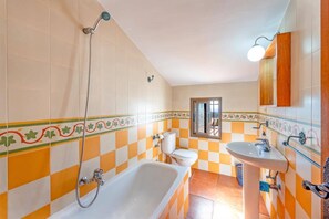 A bathroom with a checkered tile pattern, a bathtub, a toilet, and a sink. - Villa Paraiso by Villa Plus (Frigiliana)
