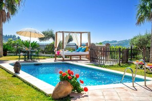 A pool area with a wooden deck, a lounge chair, a canopy bed, and a view of the hills. - Villa Paraiso by Villa Plus (Frigiliana)