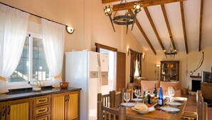 Una cocina acogedora con armarios de madera, una mesa de comedor preparada para seis personas y una araña.
