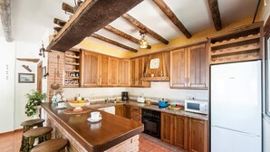 Una cocina con armarios de madera, una isla de ladrillo y un refrigerador blanco.