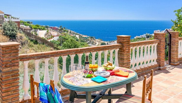 Una terraza con mesa lista para comer, con vistas a la costa.