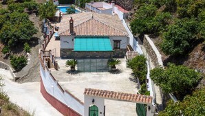Una villa con piscina, un portón verde y un muro de piedra.