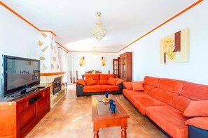 Uma sala de estar com televisão, sofá, mesa de centro, lareira e obras de arte.