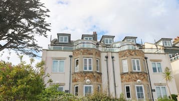 Un edificio de varios pisos con fachada de piedra, numerosas ventanas y un balcón.