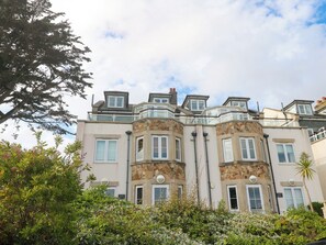 A multi-story building with a stone facade, multiple windows, and a balcony.