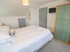 A bedroom with a bed, a wardrobe, a television, and a door.