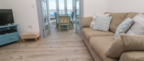 A living room with a sofa, a television, and a dining area with chairs and a table.