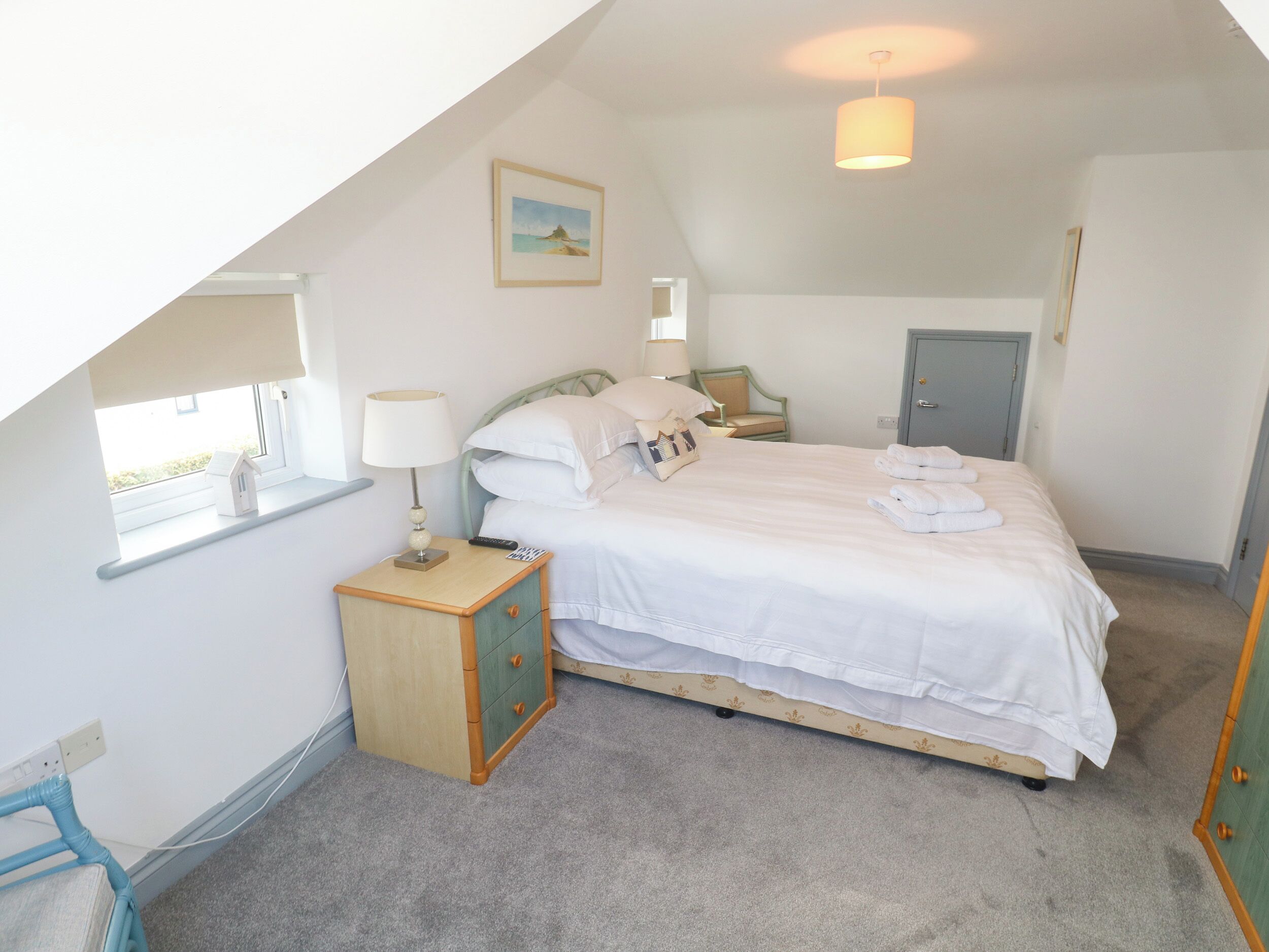 A bedroom with a single bed, bedside table, lamp, and a window.