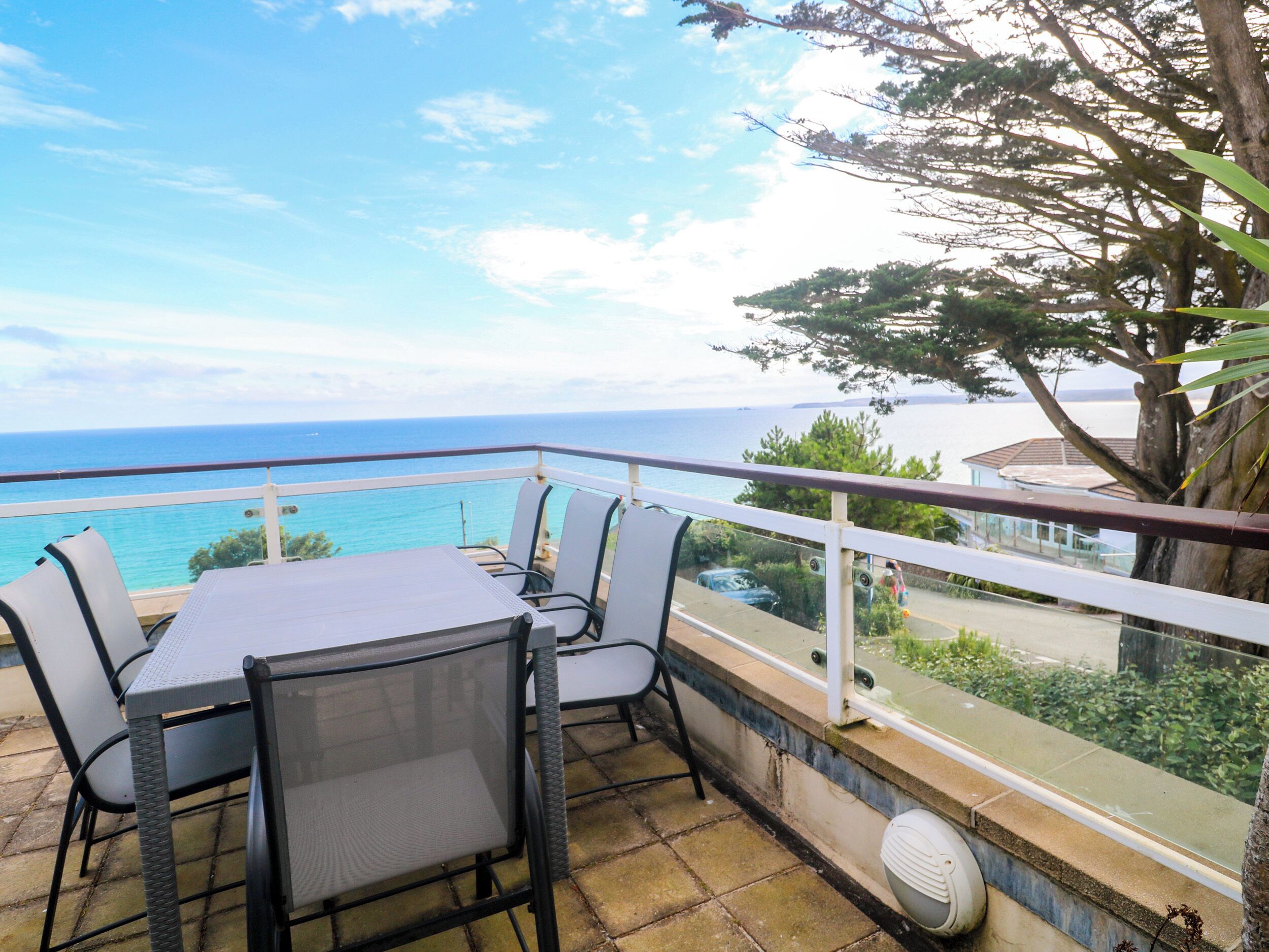 A balcony with a table and chairs overlooking a coastal view.