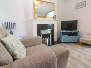 A living room with a sofa, a television, a fireplace, and a blue cabinet.