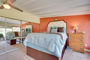 Una camera da letto con un letto, una cassettiera, uno specchio e una ventola a soffitto.