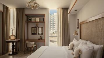 A hotel room with a large bed, a desk with a chair, a bookshelf, and a view of the outside.