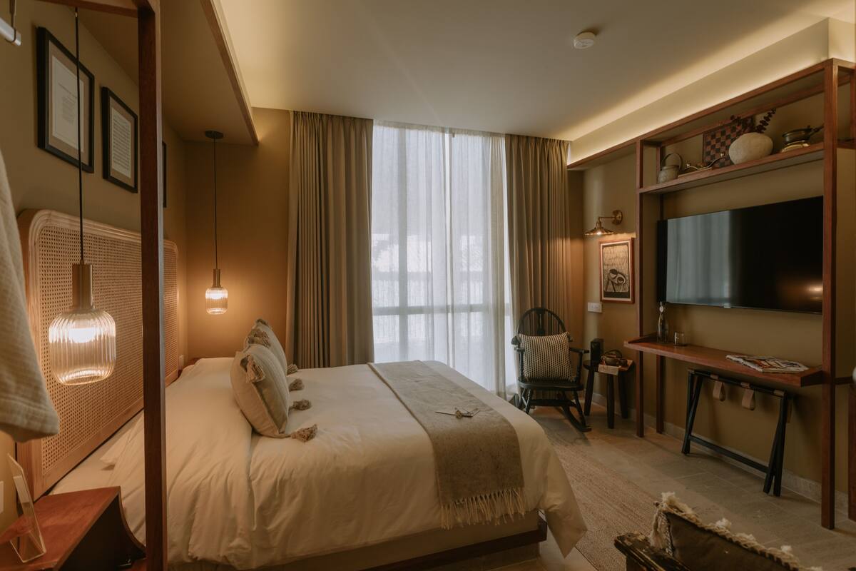 A hotel room with a large bed, a television, a desk, and a chair.