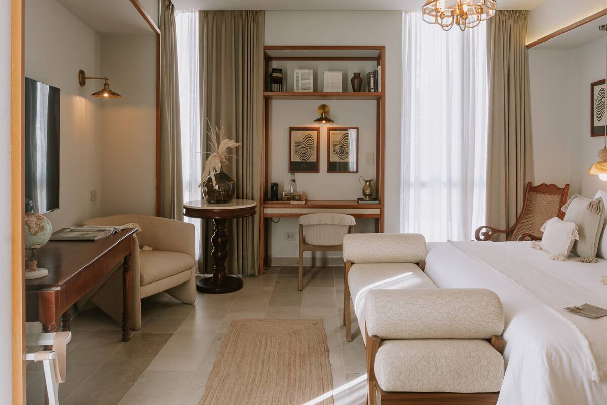 A modern bedroom with a bed, desk, chair, and a large mirror.