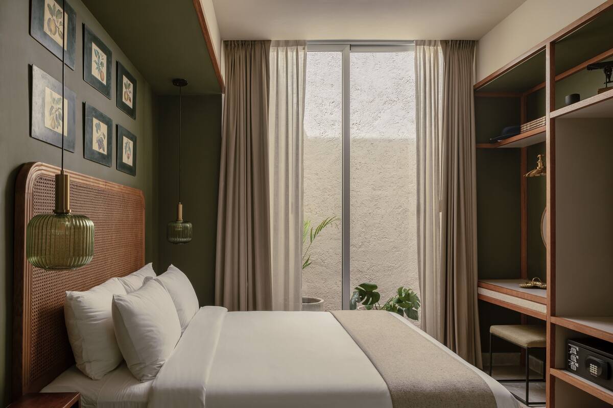 A neatly arranged bedroom with a large bed, a wardrobe, and a window with curtains.