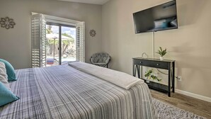 Une chambre à coucher avec un lit, une télévision, une chaise et une fenêtre avec des volets.