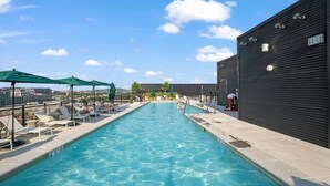 Une piscine sur le toit, avec une eau d’un bleu limpide, des chaises longues et des parasols.