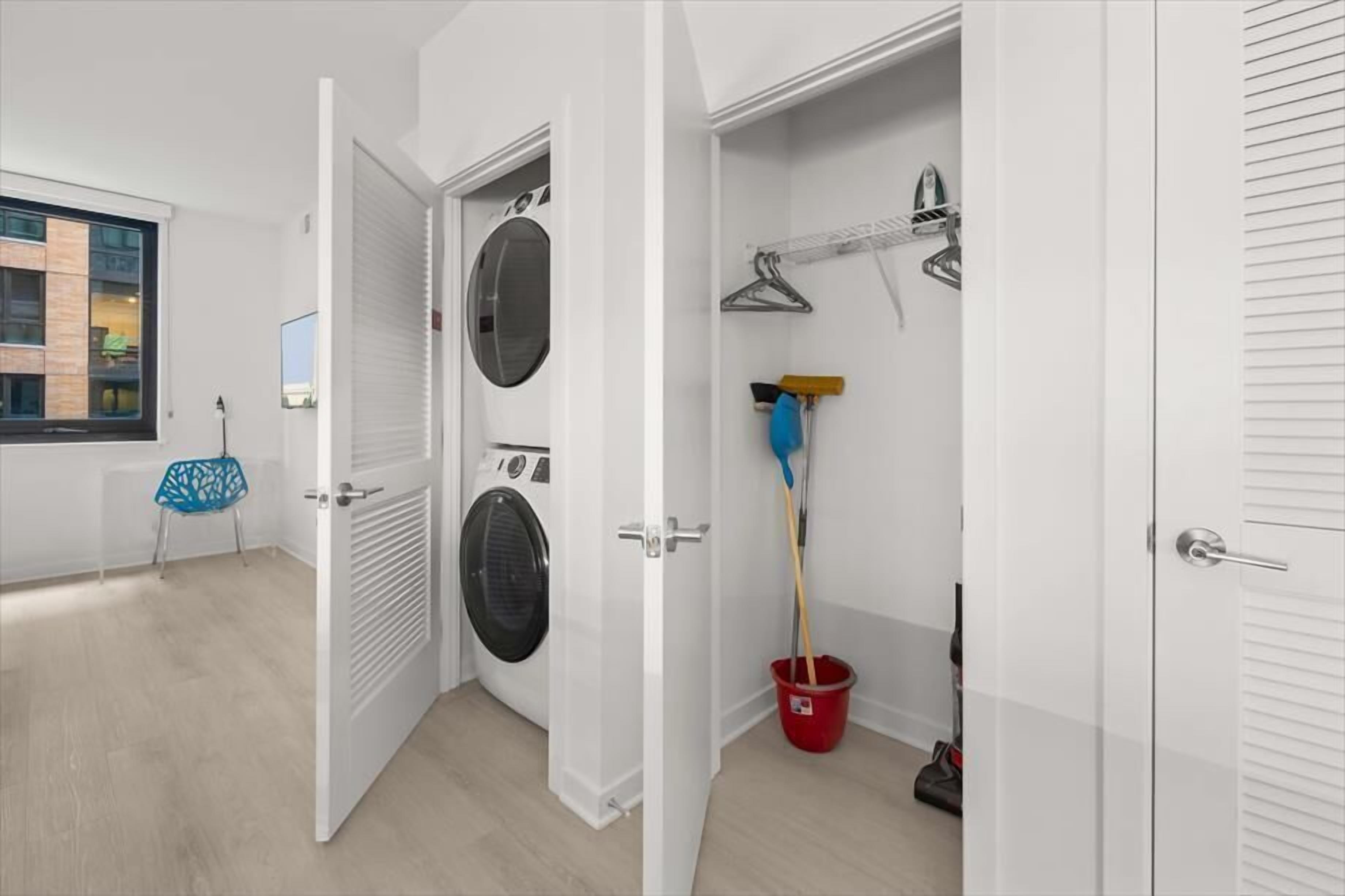Een wasserette met een wasmachine, een droogrek en een emmer.