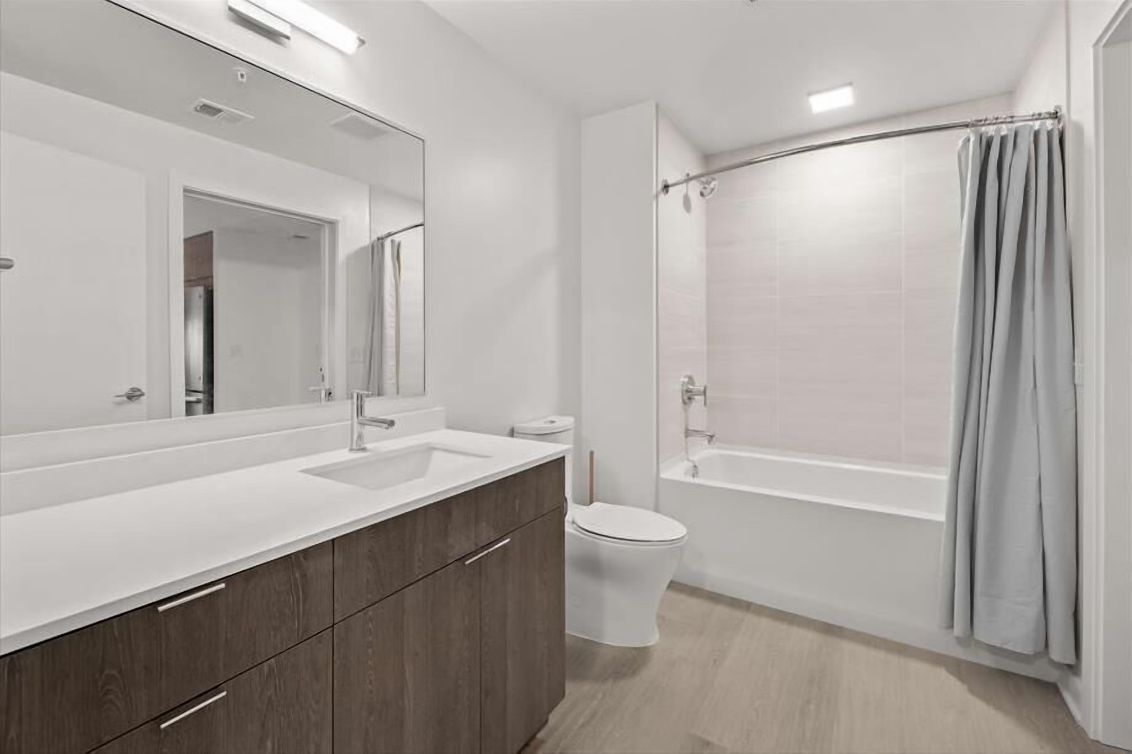 Een moderne badkamer met een grote spiegel, twee wasbakken, een toilet en een bad.