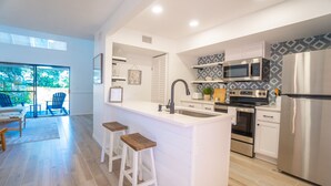 Una cocina moderna con armarios blancos, electrodomésticos de acero inoxidable y una isla grande con taburetes de bar.