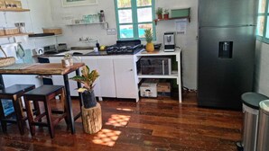 A compact kitchen with a refrigerator, a coffee machine, and wooden flooring. - Beautiful Cabin with private dock in Bacalar Lake (Buenavista)