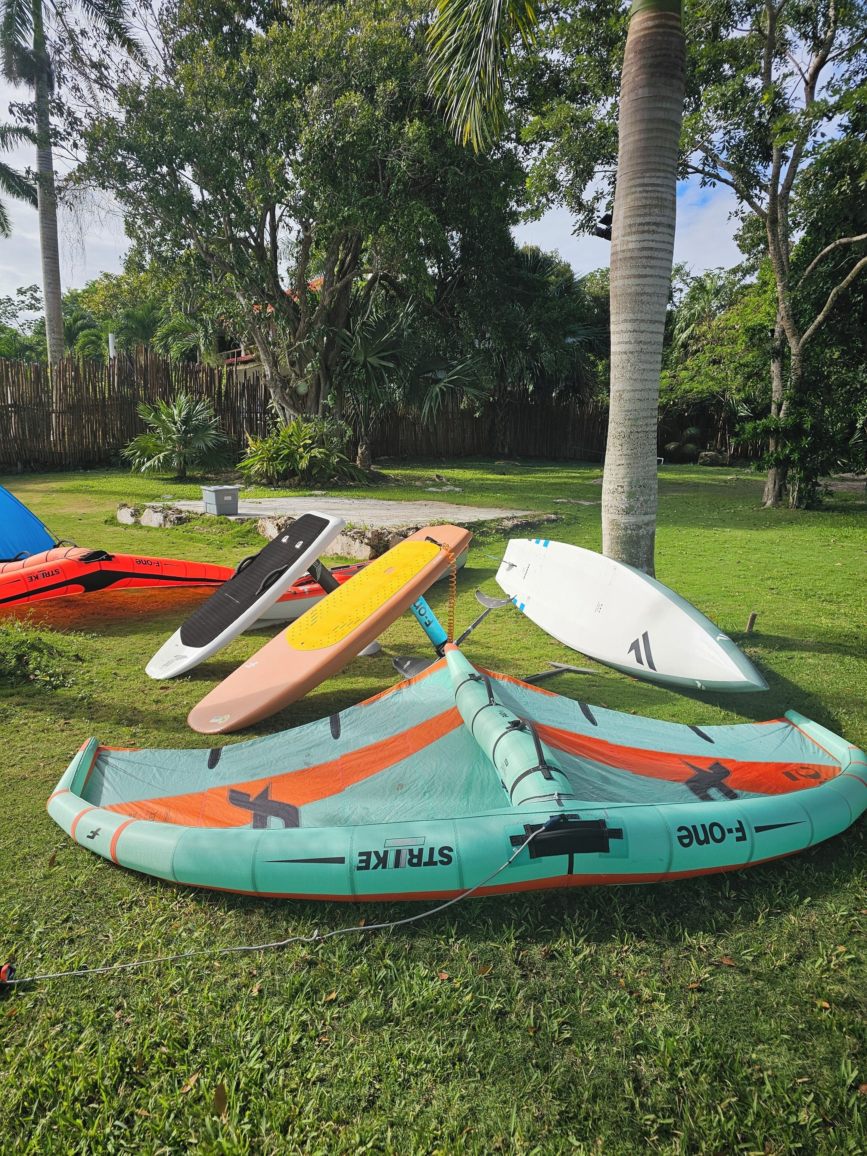 A grassy area with several inflatable kayaks and a paddleboard.