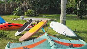 A grassy area with several inflatable kayaks and a paddleboard.
