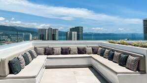 Terraço no telhado com área de estar em curva e vista para a cidade.