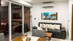 Uma sala de estar moderna com um sofá, uma mesa de jantar com velas e uma janela ampla.