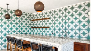 Uma cozinha com ladrilho decorativo, bancada de mármore e banquetas.