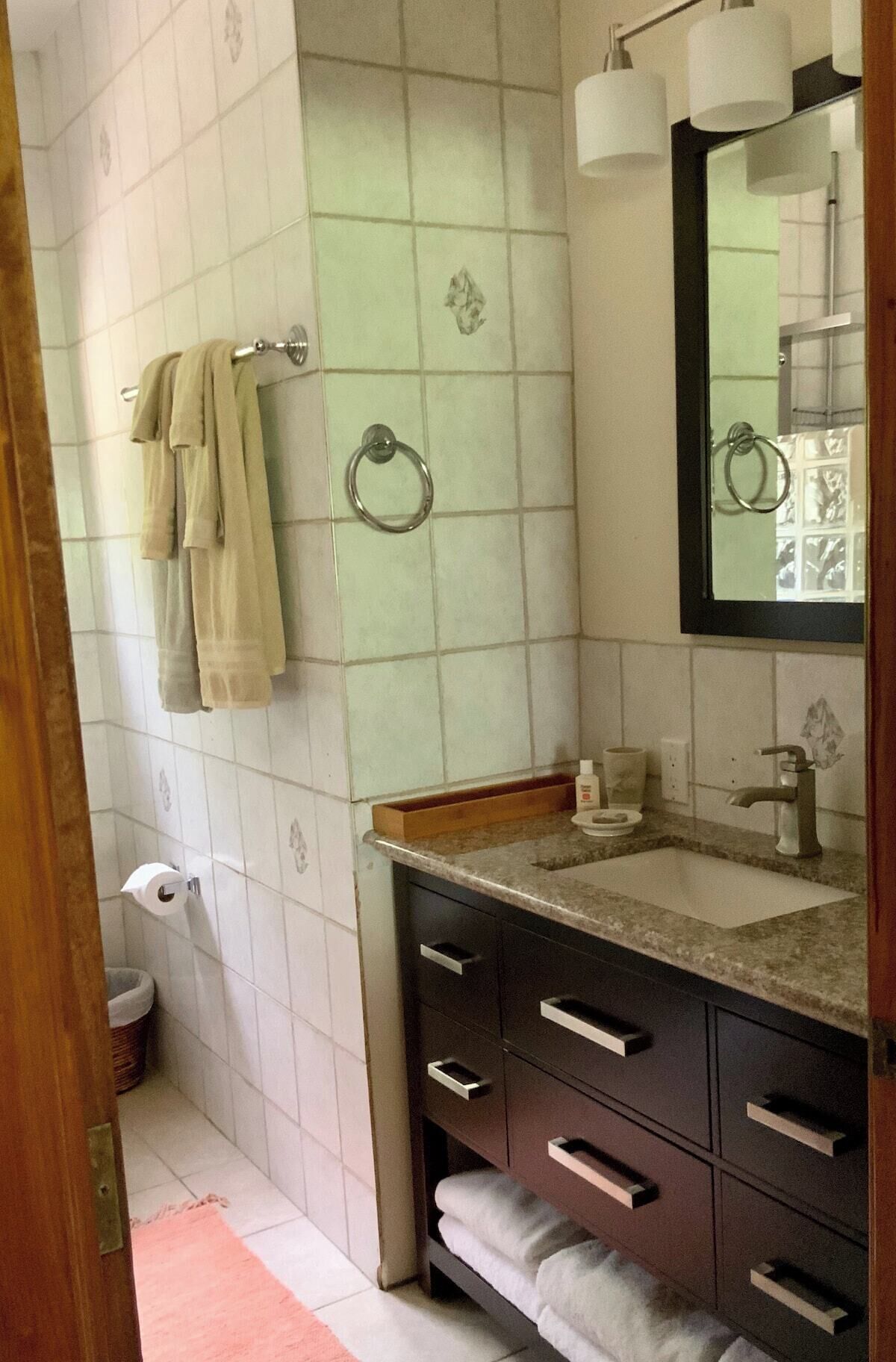 Een badkamer met een wastafel, spiegel, handdoekhouder en toilet.