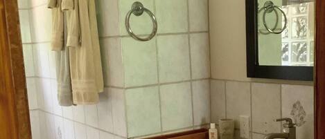 Een badkamer met een wastafel, spiegel, handdoekhouder en toilet.