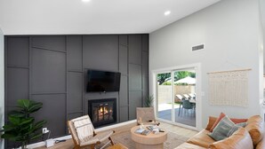 Ein modernes Wohnzimmer mit Kamin, Ledersofa und Flachbildfernseher.