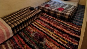 A small, cozy room with a bed, a window with bars, and a colorful rug.